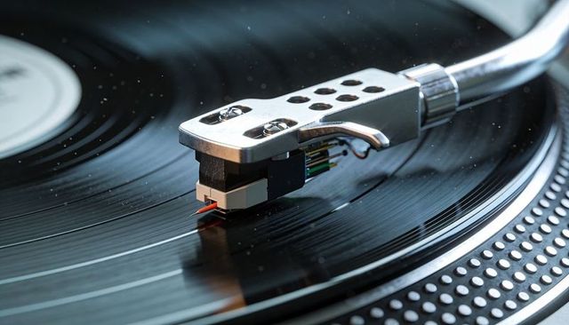 Turntable tonearm riding vinyl grooves closeup macro stylus cartridge on record