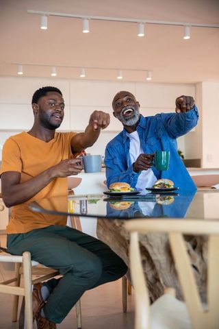 Father and Son Enjoying Relaxing Meal Together in Kitchen