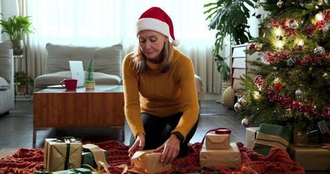 Mature Woman Arranging Gifts by Christmas Tree in Cozy Living Room