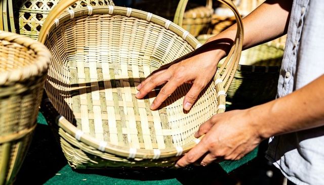 Market vendor handcrafting large woven bamboo basket in sunlight for rustic home storage