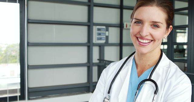 A young Caucasian female doctor is smiling confidently in a medical facility, with copy space. Her professional attire and stethoscope suggest a commitment to healthcare and patient well-being.