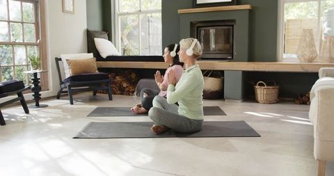 Senior Women Meditating with Headphones in Sunlit Living Room