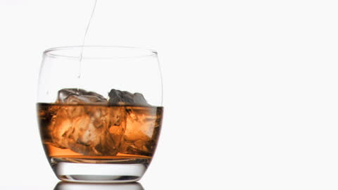 Slow Motion Whiskey Pouring into Crystal Glass with Ice