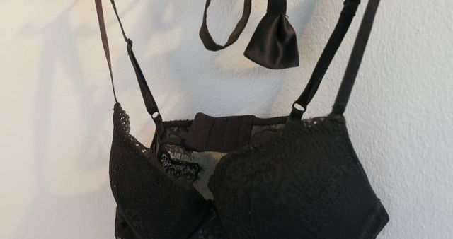 Black bra and bow hanging on hanger rack, copy space. Clothes, hanging and hanger rack concept, unaltered.