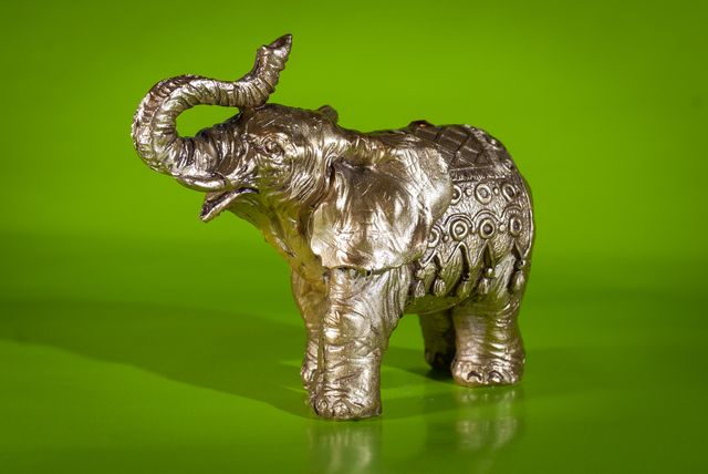 Silver Elephant Figurine with Raised Trunk on Green Background - Download Free Stock Photos Pikwizard.com
