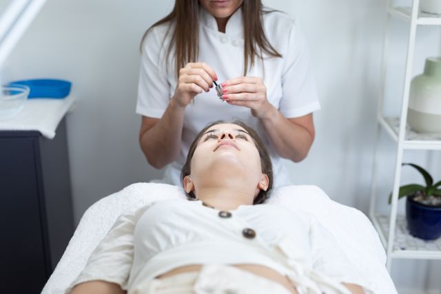 Beautician preparing for a facial treatment for a woman in a spa, emphasizing professional skincare services. Great for advertising beauty salons, skincare products, wellness centers, and articles focusing on beauty routines, relaxation, and self-care practices.
