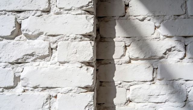 Weathered White Brick Corner with Peeling Mortar and Dramatic Diagonal Shadow