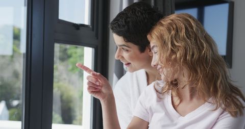 Smiling Lesbian Couple Enjoying Sunny Window View