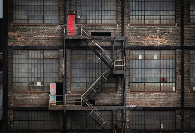 Rustic fire escape on an abandoned industrial building, showcasing urban decay. Ideal for urban exploration concepts, architectural references, grunge and gritty-themed projects, and background designs.