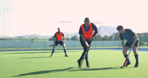 Diverse male field hockey team training on turf field