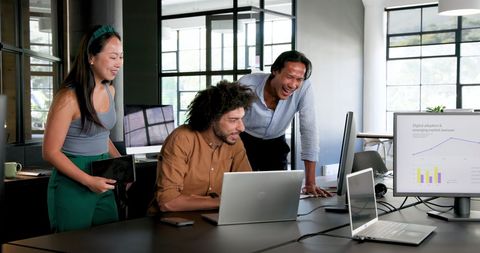 Diverse Team Collaborating in Modern Office with Laptops and Charts