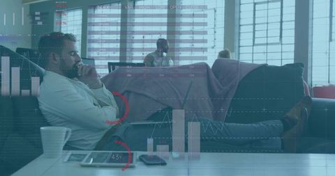 Bearded man pondering data analytics reclining on sofa with tablet and charts overlay