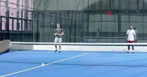 Energetic Tennis Match Between Friends on Blue Court