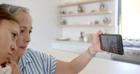Multigenerational Bonding: Asian Grandmother and Child Taking Selfie in Kitchen
