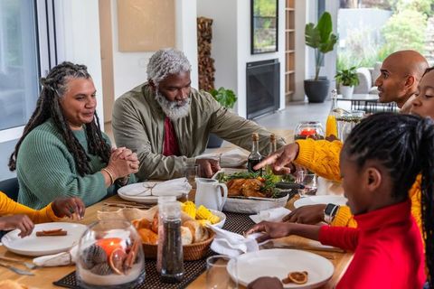 African american family gathering sharing roasted bird dinner, multigenerational holiday warmth