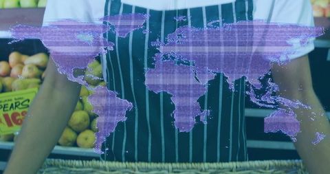 Retail worker arranging pears in striped apron with holographic world map overlay