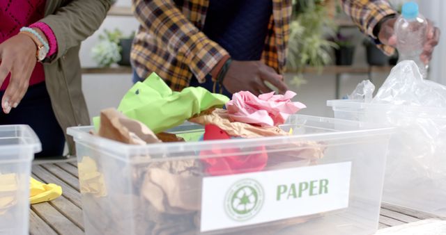 Individuals sorting paper and plastic in clearly marked recycling bins. This sustainable practice promotes environmental conservation and supports waste management efforts. Ideal for use in articles, blogs, and campaigns focused on green initiatives, sustainability, community involvement, and recycling programs.