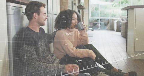 Couple sitting on modern kitchen floor sipping coffee with augmented reality hud overlay