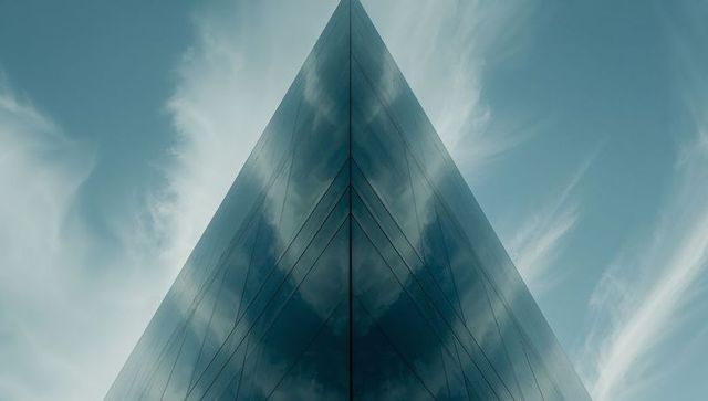 Modern glass skyscraper reflecting dramatic sky