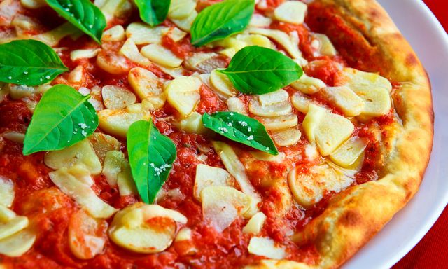 This close-up of a Margherita pizza showcases a delicious blend of tomato sauce, mozzarella cheese, and fresh basil. Ideal for food blogs, recipe websites, Italian restaurant menus, advertisements for gourmet food, or culinary magazines. The vivid colors and detailed textures highlight the pizza's appetizing appearance.