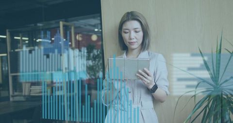 Asian Executive Reviewing Digital Analytics on Tablet in Modern Office