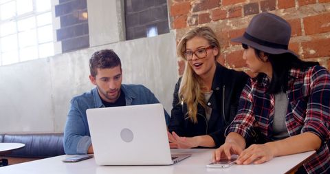 Young Adults Collaborating in Modern Workspace with Laptop