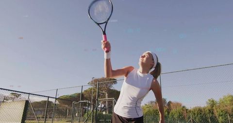 Female Tennis Player Serving at Outdoor Court on Sunny Day