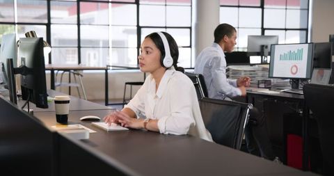 Focused Businesswoman with Headphones in Modern Office Workspace