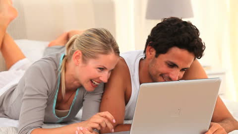 Couple Relaxing in Bed with Laptop