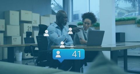 Collaborating professionals pointing at laptop in coworking space with 41 followers badge