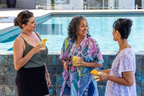 Diverse women enjoying poolside citrus drinks and lively conversation on sunny day