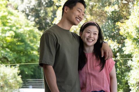 Asian couple laughing and embracing on sunny balcony enjoying outdoor casual lifestyle
