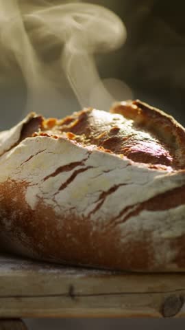 Zooming on Steaming Artisan Sourdough Loaf on Wooden Plank Highlighting Flour Dust