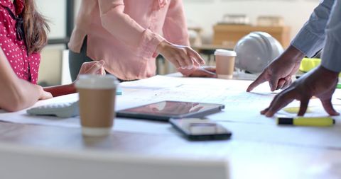 Diverse Architects Collaborating on Blueprints in Modern Office