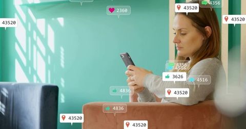 Woman checking smartphone receiving social media notifications in cozy teal living room