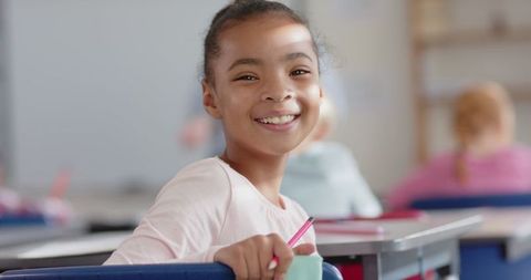 Happy student smiling at desk in classroom setting