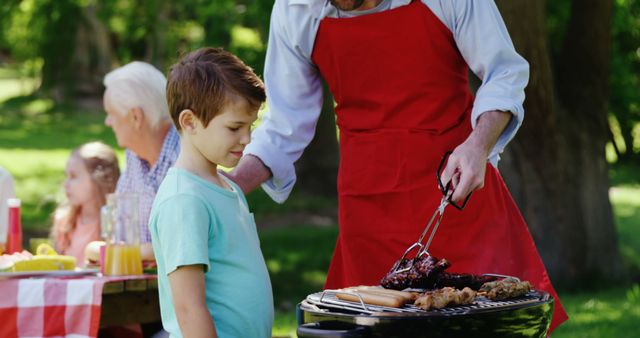 Father and son preparing food on barbecue in the park