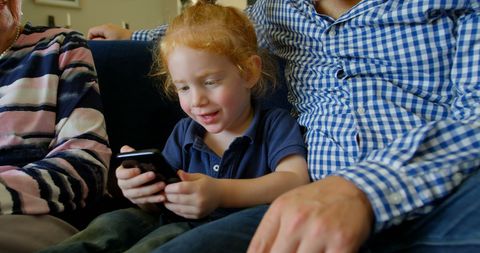 Little Girl Using Smartphone with Family on Living Room Sofa - Download Free Stock Images Pikwizard.com