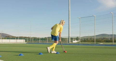 Female athlete practicing field hockey dribbling on turf
